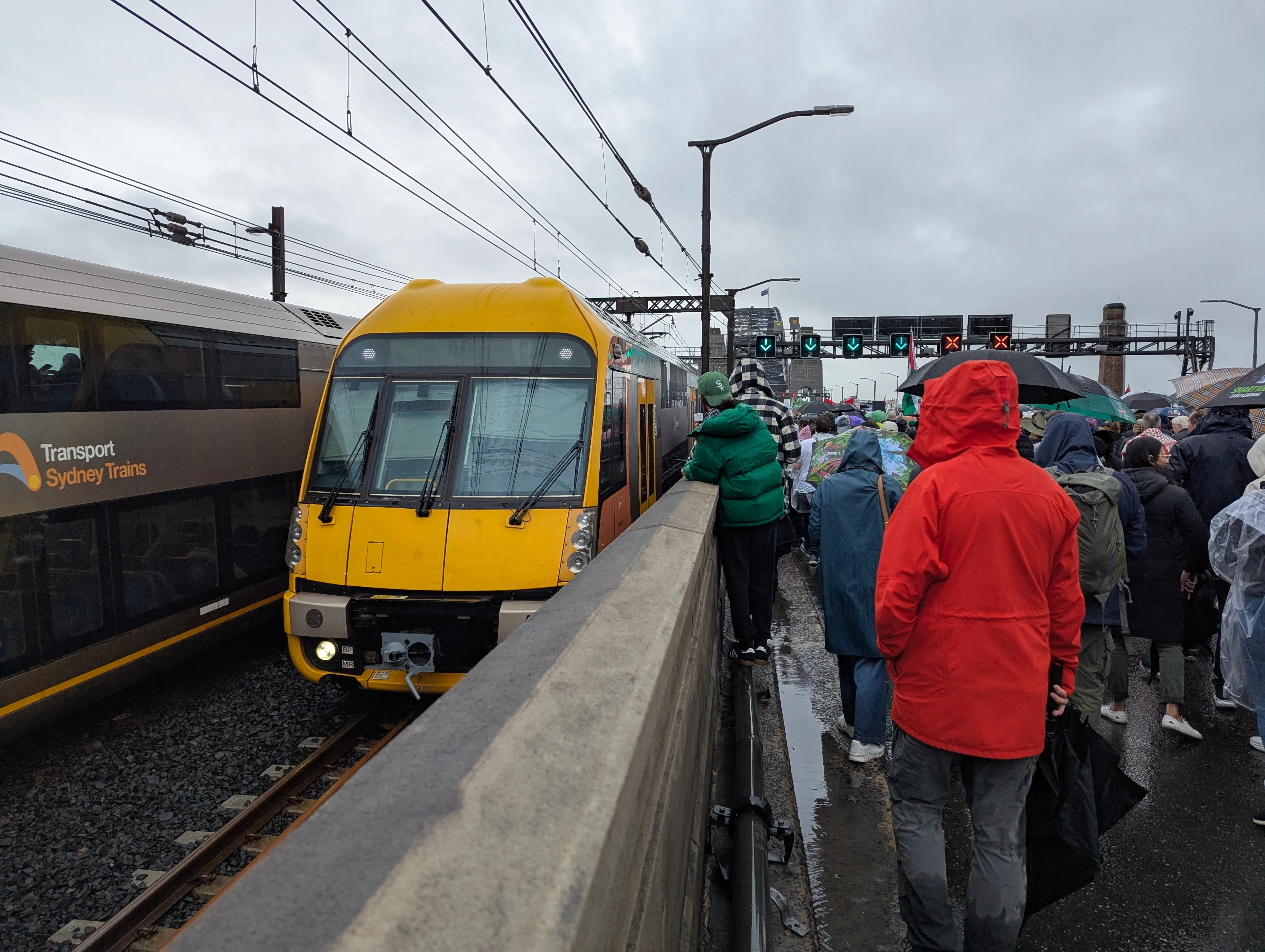 A yellow and grey double decker Waratah Series 1 train on the Harbour Bridge taken from the car lanes during the March for Humanity.