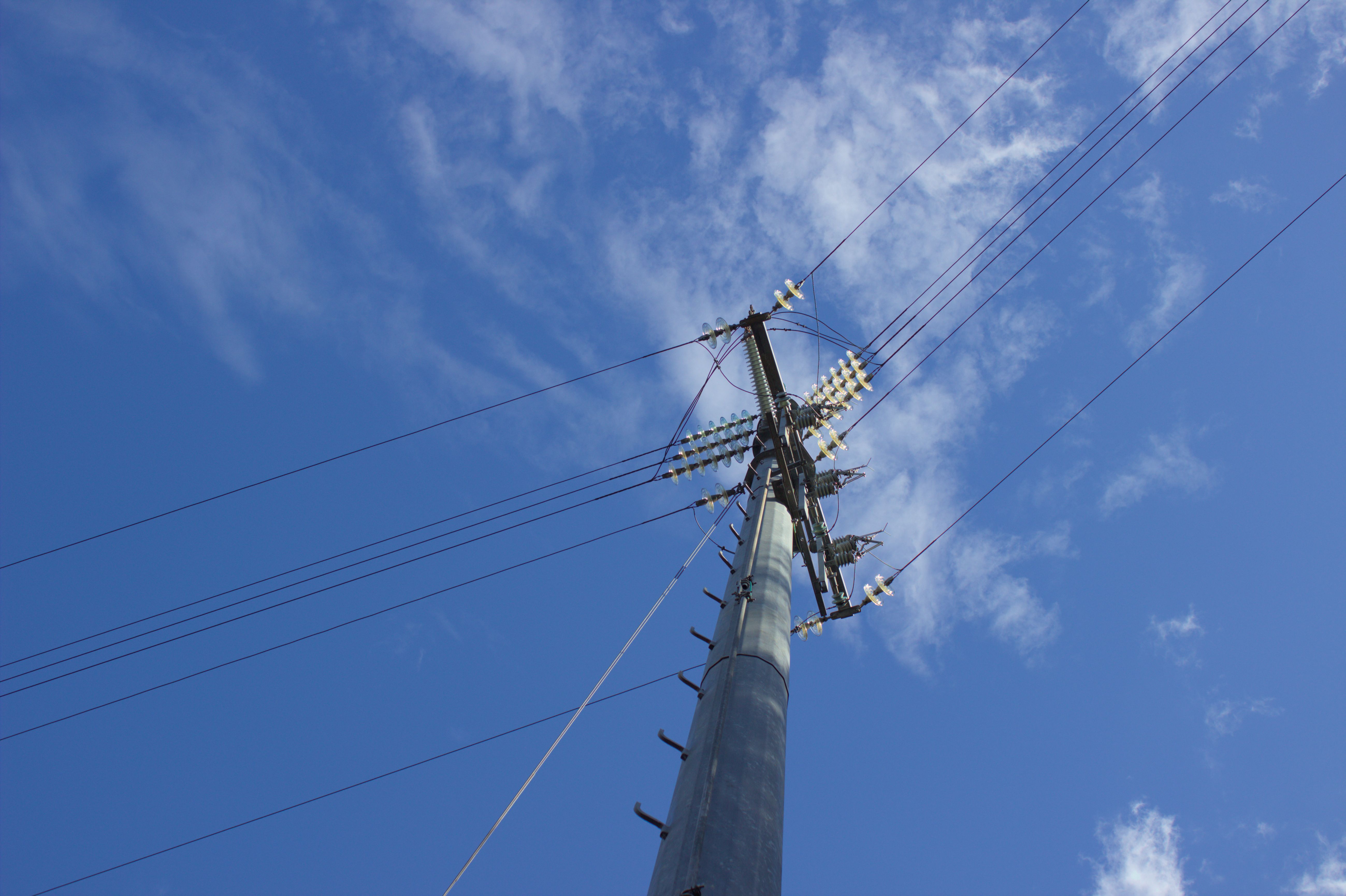 A steel electrical pole shot from a low angle so that only the top pole, wires and sky are visible.