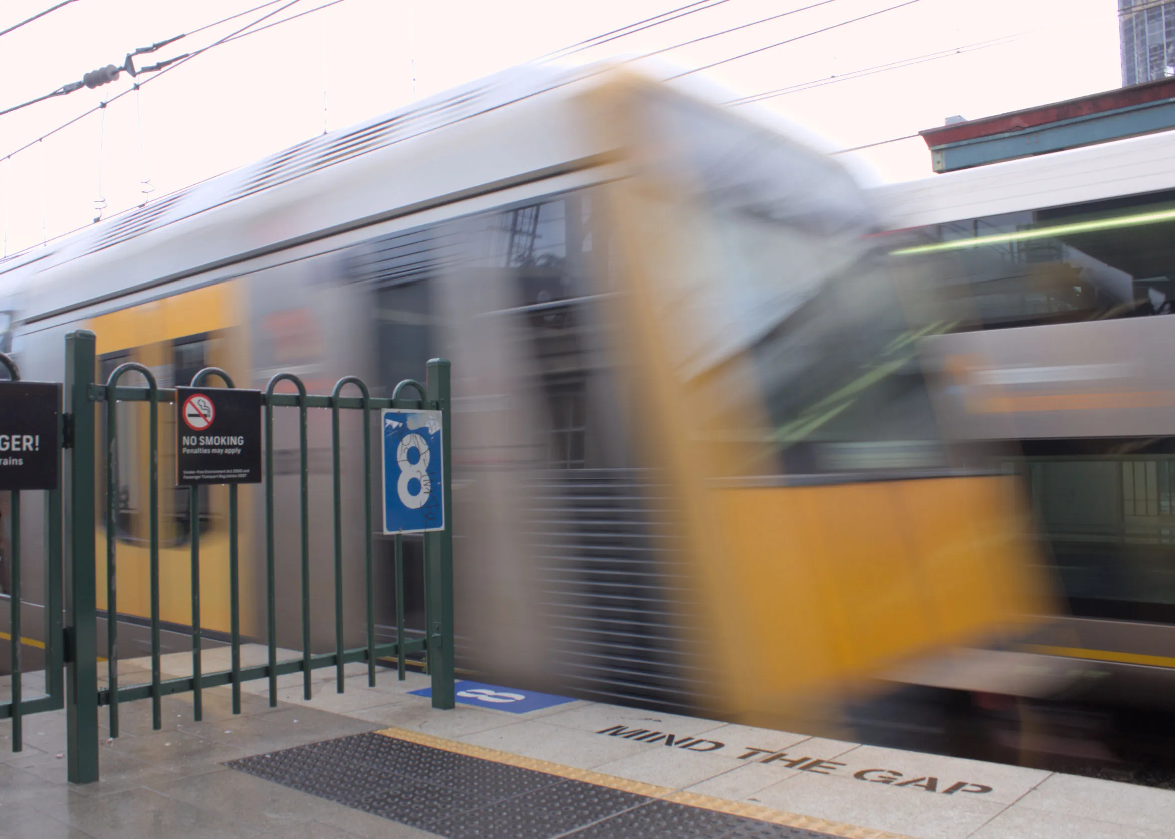 The blurry rear of a T set departing the platform at Central at speed
