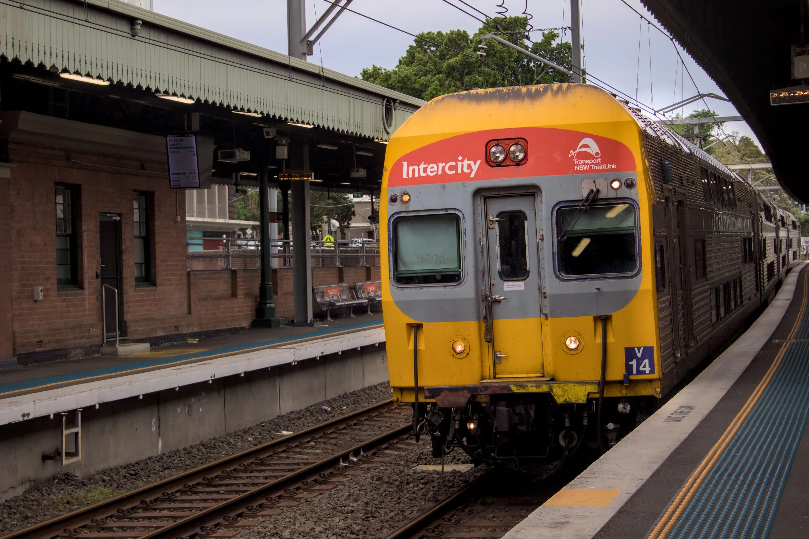 An Blue Mountains line run serviced by 4-car V14 pulls into the platform at  Strathfield station on an overcast day